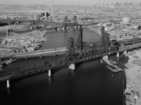 Aerial view of the vertical lift bridges spanning the Hackensack river, looking northeast. The PATH transit bridge is in the foreground, with the Conrail, Newark Turnpike, and Erie & Lackawanna railroad bridges behind it