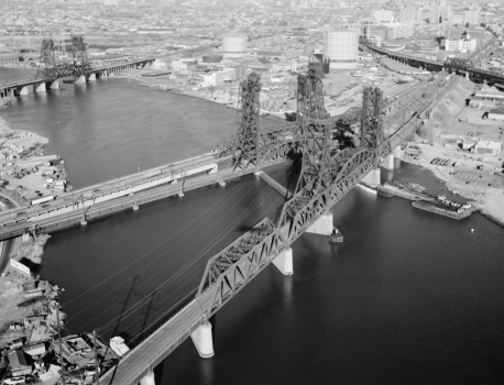 Aerial view to the east of the PATH transit system bridge over the Hackensack river. In the background, from left to right, are the Erie & Lackawanna railroad bridge, the Newark turnpike, and the Conrail bridge. The Pulaski Skyway is in the background to the right