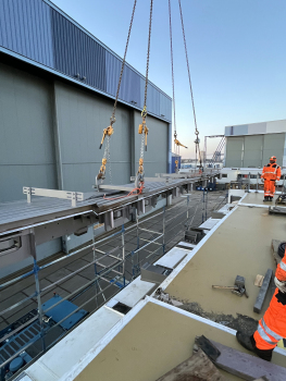 Le joint lors du levage sur la jetée à Rotterdam : En bas à l'avant, la table sur le pont où repose la construction est blanche, avec les tôles de glisse-ment sombres sur lesquelles la construction glisse.