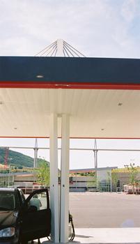 Millau Viaduct: A nearby Intermarché supermarket has installed a gas station with a cable-stayed roof that is supported by pylons molded after the viaduct which can be seen in the background