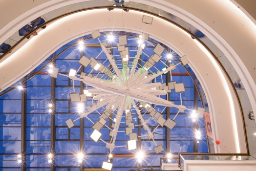 Mit 18,5 Metern erstreckt sich die OLED-Installation über alle drei Verkaufsebenen bis unter das gläserne Dach – und ist damit eine der gößten ihrer Art weltweit. "The Source" besteht aus 36 einzelnen Plattformen mit einer Spannweite von zwei Metern, die jeweils 12 organische LEDs tragen. Einzeln ansteuerbar ermöglichen sie faszinierende Farbwechsel und kreative Lichtspiele. Für " The source" entwickelte Carl Stahl Architektur ein durchdachtes Trägersystem: spezielle Drahtseile mit zwölf Millimetern Durchmesser, befestigt an einer vom Glasdach abgehängten Kreuztraverse, nehmen die 36 Ebenen auf. 36 Kragarmelemente, LED-Trägersysteme und Gehäuse dienen der Befestigung der insgesamt 432 Lumiblade OLEDs von Pilips