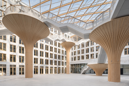 EDGE Südkreuz : The four office blocks of the Carré enclose an inner courtyard with a unique atmosphere, which, with its supports modeled on nature and an airy canopy of foil cushions, is designed to create an identity. The tree as the donor of the building's characteristic construction material, wood, is both materially and symbolically at the center of the architecture here.