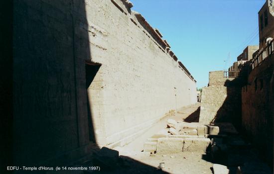 Edfou - Temple d'Horus, mur d'enceinte Est, à droite la ville actuelle domine la base du temple de plusieurs mêtres