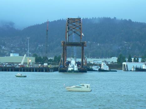Mounted on a barge, the tied-arch main span of the new Sauvie Island Bridge leaves Portland's Terminal 2 on the Willamette River
