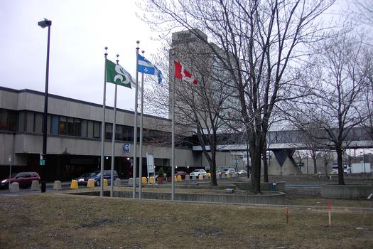 Ligne jaune du Métro de Montréal - Vue extérieures du terminus Longueuil; devant une passerelle couverte menant à un complexe commercial et d'habitations