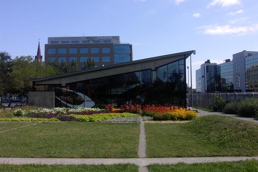 Station Champs-De-Mars; Vue sur des jardins floraux situés côté Ouest de l'édicule de la station; à droite, juste en dessous de l'édifice vitré, on voit la passerelle franchissant l'autoroute Ville-Marie (A-720) ce qui permet au aux fonctionnaires municipaux et autres piétons, d'accéder à l'hôtel de ville et au Vieux-Montréal. 17/31 Ligne Orange Métro de Montréal