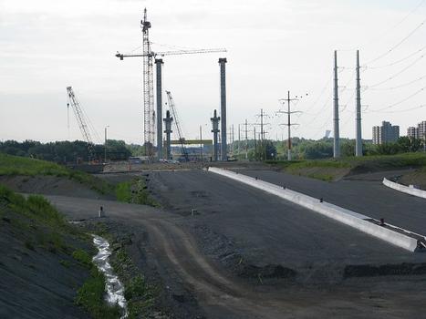 Construction des pylônes à haubans du pont de l'autoroute A-25; à l'avant plan construction d'une section de l'autoroute L-H Lafontaine à Laval échangeur Lévesque; photo au téléobjectif prise depuis le viaduc ferroviaire de Canadien-Pacifique