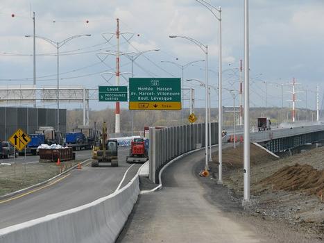 Sur le côté aval, piste cyclable de trois mètres de largeur accédant au pont de la A-25, finalisation des travaux de terrassement et d'aménagement paysager à droite