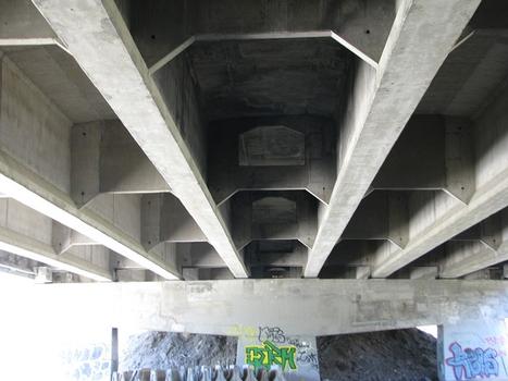 Vue en dessous du tablier du pont; poutres de béton précontraint perpendiculairement contreventées d'entretoises qui sont elles aussi en béton
