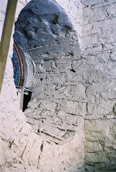View of the interior rock walls inside the dome. The cirular window is a stained glass window visible from inside the dome. The light coming from the right side is from one of the exterior windows of the dome