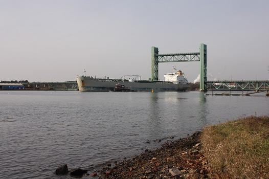 A navy vessel passes beneath the open lift span
