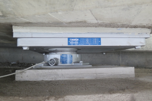 A newly installed pot bearing with integrated pressure sensor and cable connection point for use of portable monitoring unit (also showing a large preset to pre-compensate transverse deck movements)