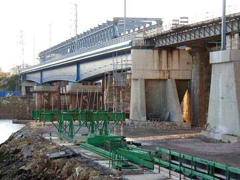 Eisenbahnbücke Lorient: Eine Hälfte der neuen Brücke auf Hilfspfeilern während die alte Brücke rückgeschoben wird. Der Eisenbahnverkehr läuft eingleisig auf der neuen Brücke weiter