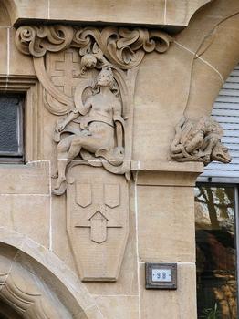 Metz - Immeuble 9 avenue Foch - Détail: une représentation lascive de la Lothringer Baugesellschaft assice sur les emblèmes du constructeur et se tournant vrs une croix de Lorraine. Dragon gardant la fenêtre