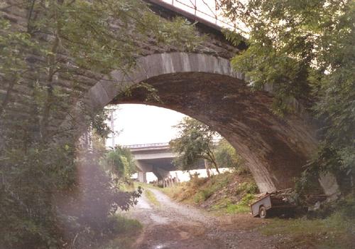 Le pont de la voie ferrée désaffectée sur la N937 à Sovet (province de Namur) : En arrière-plan, le viaduc de Sovet de l'autoroute E411