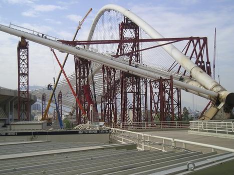 OAKA Olympic Stadium (2004): The roof hangs in a giant arc of 80 m high. Each arc consists of two 3,5 m diameter tubes with a span of 304 m and support the new state-of-the-art roof. Movement of arc and roof construction weighing 8500 ton is done simultaneously using Enerpac PLC-controlled hydraulic systems with four 150 ton pull cylinders with 2 m stroke. These double-acting cylinders are attached to shoes in a sliding and guiding system pulling the arc with roof assembly step-by-step into the final position