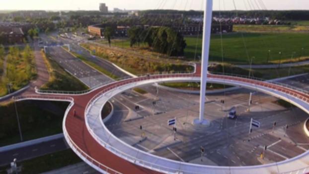 bird's-eye view Hovenring Eindhoven (the Netherlands) designed by ipv Delft:This spectacular circular cycle bridge in the Dutch city of Eindhoven has recently been opened to the public. The cable-stayed bridge, designed by ipv Delft, offers cyclists and pedestrians an exciting crossover. With its impressive pylon, 72 metre diameter, thin deck and conspicuous lighting, the cyclist roundabout is a new landmark for the city.
http://www.youtube.com/watch?v=wYbOLOOi-tk