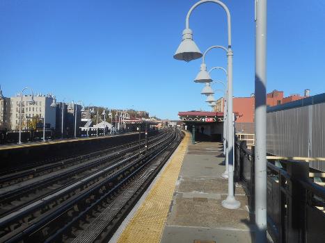 238th Street Subway Station (Broadway – Seventh Avenue Line):View of the platforms and all three tracks from the Van Cortlandt Park-242nd Street-bound platform of the 238th Street Elevated Railway Station on the IRT Broadway – Seventh Avenue Line between the Riverdale and Kingsbridge sections of the West Bronx, New York City. This image includes a standard Helvetica New York City Subway exit sign over the 242nd Street-bound canopy, and is the fifth in a series of additional images of the station, all of which were taken on November 24, 2021. If you zoom in towards the center of the tracks off in the distance, you could even see the 242nd Street station at the end of the line.