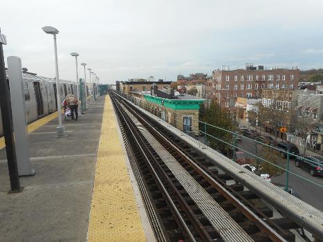 Norwood Avenue Station:Looking west along the center of the platform of the Norwood Avenue Elevated Railway station on the BMT Jamaica Line in the Cypress Hills section of Brooklyn, New York City, while a Jamaica-bound train discharges passengers. Along side that building with the green roof trim, is Arlington Avenue as seen from above Hale Avenue.