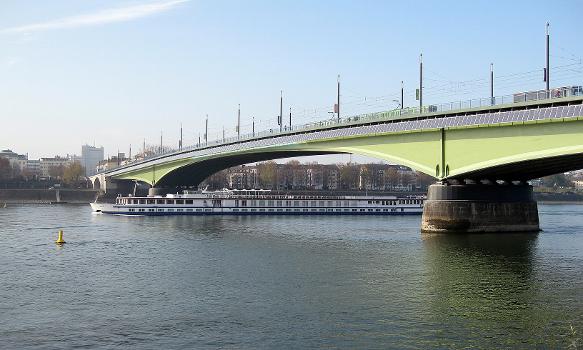 Kennedybrücke über den Rhein in Bonn : Die Brücke verbindet das rechtsrheinische Bonn-Beuel (bis Juli 1969 selbstständige Stadt) mit Bonn-Zentrum. Während einer dreijährigen Umbauphase (von 2007 bis 2010) wurde sie saniert und verbreitert. Von März bis April 2011 wurde an der Südseite der Brücke - über die gesamte Breite des Bauwerks - eine Solaranlage zur Stromgewinnung angebracht, die die erste an einer Flussbrücke in Europa sein soll. Sie wurde von der ortsansässigen Fa. Solarworld AG gespendet. Die zu erwartende Einspeisevergütung soll nach dem Willen des Sponsors jährlich einer wechselnden lokalen Organisation gespendet werden.