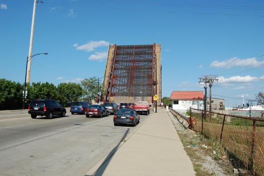 The 95th Street Bridge, over the Calumet River in Chicago, is a 1958 double-leaf bascule bridge : In this photo, the bascule span is raised to allow river traffic to pass.