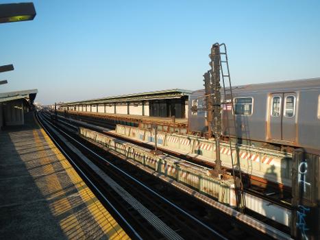 Looking northeast at arriving northbound F train on a sunny afternoon