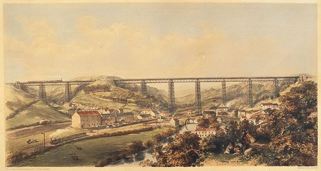 A view of the viaduct and the valley at Crumlin : Trains can be seen crossing over and under the bridge, and the village and river can be seen in the foreground.