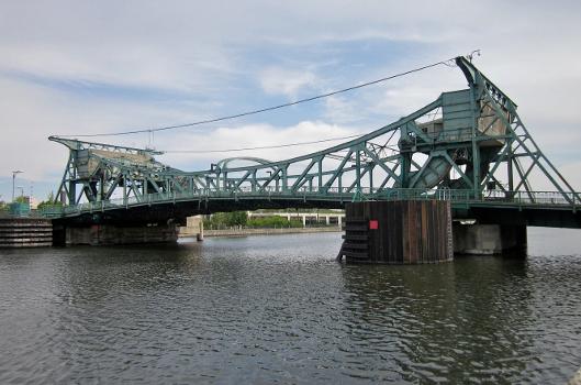 The north side of the Jefferson Street Bridge, in Joliet, Illinois, viewed from the west riverbank : It carries eastbound US Route 30. It is one of four Scherzer Rolling Lift bascule bridges in Joliet, all of which span the Des Plaines River.