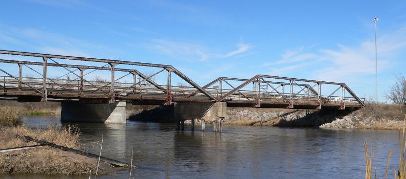 Two of the three spans of the Kilgore Bridge in Buffalo County, Nebraska:The bridge crosses the north channel of the Platte River beside Nebraska Highway 10. The picture was taken facing northwest (upstream). The Pratt pony truss bridge was built in 1915 by the Nebraska Department of Roads. Highway 10 now crosses the river on a concrete bridge just upstream (one pier of which visible under the bridge). Until 2009, the Kilgore Bridge carried local traffic to a frontage road beside Interstate 80 north of the river; however, it is now closed to motor traffic. The bridge is listed in the National Register of Historic Places.