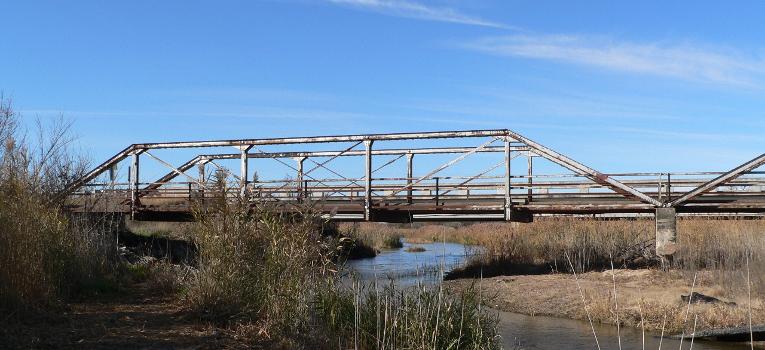 One of the three spans of the Kilgore Bridge in Buffalo County, Nebraska : The bridge crosses the north channel of the Platte River beside Nebraska Highway 10. The picture was taken facing northwest (upstream). The Pratt pony truss bridge was built in 1915 by the Nebraska Department of Roads. Highway 10 now crosses the river on a concrete bridge just upstream. Until 2009, the Kilgore Bridge carried local traffic to a frontage road beside Interstate 80 north of the river; however, it is now closed to motor traffic. The bridge is listed in the National Register of Historic Places.