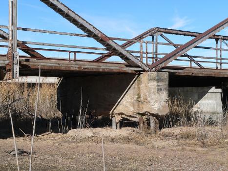 Detail of Kilgore Bridge in Buffalo County, Nebraska : The bridge crosses the north channel of the Platte River beside Nebraska Highway 10. The picture was taken facing northwest (upstream). The Pratt pony truss bridge was built in 1915 by the Nebraska Department of Roads. Highway 10 now crosses the river on a concrete bridge just upstream. Until 2009, the Kilgore Bridge carried local traffic to a frontage road beside Interstate 80 north of the river; however, it is now closed to motor traffic. The picture shows damage to one of the bridge's piers. The bridge is listed in the National Register of Historic Places.