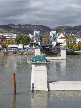 Neubau Eisenbahnbrücke Linz:Die Neue Linzer Donaubrücke (Projektname) ist der Ersatz der 2016 abgetragenen Eisenbahnbrücke. Sie wurde nach einem Design des Pariser Architekturbüros Mimram gebaut. Die Vormontage erfolgte an linken Donauufer.