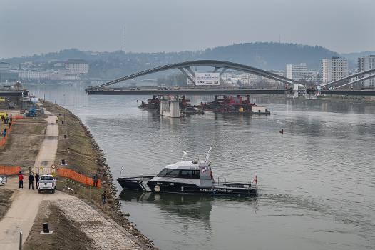 Neubau Eisenbahnbrücke Linz:Die Neue Linzer Donaubrücke (Projektname) ist der Ersatz der 2016 abgetragenen Eisenbahnbrücke. Sie wurde nach einem Design des Pariser Architekturbüros Mimram gebaut. 
Der Transport der Brückenelemente vom Vormontageplatz auf die Brückenpfeiler erfolgte mit Hilfe zweier Pontons und Schubschiffen.