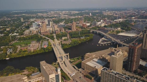 Drone shot of the Mississippi River, Nicollet Island, St. Anthony Falls, various East Bank neighborhoods : Closest bridge is Hennepin Avenue Bridge; downsteam are Central Avenue Bridge, Stone Arch Bridge, and I-35W Saint Anthony Falls Bridge.