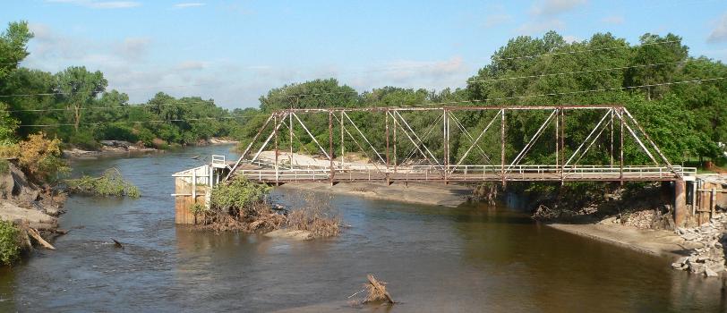 Neligh Mill Bridge : Neligh Mill Bridge over the Elkhorn River in Neligh, Nebraska; seen from the east (downstream). The pin-connected Pratt through truss bridge was constructed in 1910; it is listed in the National Register of Historic Places. The photo was taken ca. 2 weeks after major flooding on the Elkhorn in June 2010; beside the erosion south of the south abutment, note the partial collapse of the deck at the south end.