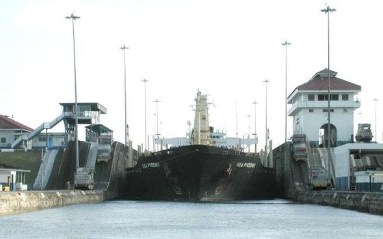 The Sea Phoenix moves between lock chambers of the Panama Canal. Although this ship is far below Panamax size, she still seems to fill the available space, particularly in this view from a small sailboat sharing the lock chamber with the ship, as she transits down the Gatun locks to the Caribbean. On either side, the ship's lines can be seen leading to mules on the lock walls — small locomotives which manoeuvre the ship within and between the lock chambers