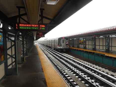 A Manhattan-bound R143 leaves the Sutter Avenue Elevated rapid transit station on the BMT Canarsie Line in the Brownsville and East New York : Taken from the Rockaway Parkway-bound platform, where another R143 L train is about to approach the station as it heads into Canarsie, followed by a second Canarsie-bound L train seven minutes from that point, barring any potential snow-related delays.
