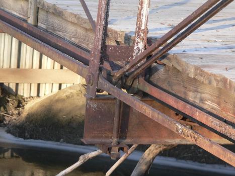 Bottom of vertical member of west truss, Sweetwater Mill Bridge in Buffalo County, Nebraska:The pin-jointed Pratt pony truss bridge carries Sweetwater Road across Mud Creek. It was built in 1909 by the Standard Bridge Company, and is listed in the National Register of Historic Places.