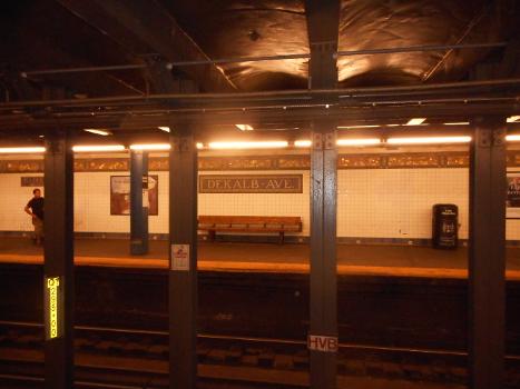 DeKalb Avenue Subway Station (Canarsie Line) : West Village-bound platforms of DeKalb Avenue (BMT Canarsie Line), as seen from the Rockaway Parkway-bound platform. This contains the traditional mosaics that were originally added to BMT subway stations, which are right over a bench.