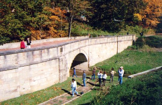 A few visitors check out the Fox Run S-Bridge from the walkway at the water's edge, below the bridge