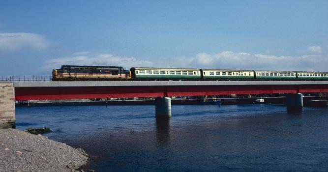 Ness Bridge:The new Ness Bridge at Inverness is crossed by Class 37 no.37409 on 22 August 1991. This is a Kyle train, which at that time was formed of this green-and-cream liveried set.