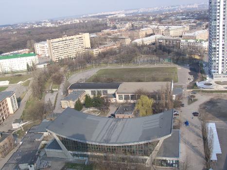 Pioneer Indoor Swimming Pool and Stadium, Kharkov, Ukraine:View from the mark of +90 m. The HVVKIURV building (now the Institute of Air Force) is behind them, Dinamovskaya Street is on the left, Sumskaya Street is perpendicular to the right. On the horizon Zhuravlevka, behind it - Saltovka (white high-rise buildings across the Kharkov River). On the right is a 25-storey residential building "Avantage" (built in 2007) on ul. Trinklera, right-to the left is Gorky Park, on the left in front of the park on the edge of the football field of the Zvezda Stadium. 
Flying object over Kharkov: In the upper left corner of the picture there is a kind of a gray flying flying shiny or unabused "oblate ball" rather big, based on the distance, the size at least 85 meters above the ground against the background of the building on the Sumy before the FED plant. This is definitely not a balloon (and a big one for this), flying meteo-probes over the city is strictly prohibited. What could it be? --Vizu 
Dear Vizu, "shiny thing" - really "shiny thing" - decoration made of metal about the height of the floor and the length of a couple of window openings, hanging (and perhaps still hanging) on ​​the same building, located near the "second tram circle" near TsPKiO them. Gorky (the so-called "backup ring").