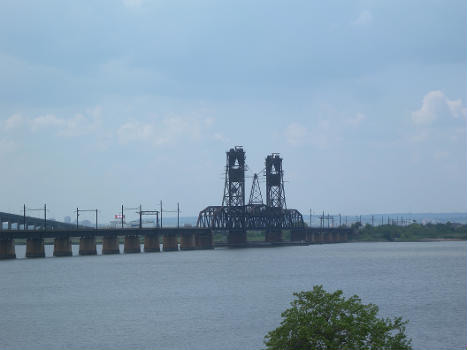 Looking west from West 63d Street overpass of Rte 440, at Lehigh Valley Railroad bridge over Newark Bay, upstream of Tunpike bridge, on a partly cloudy midday.