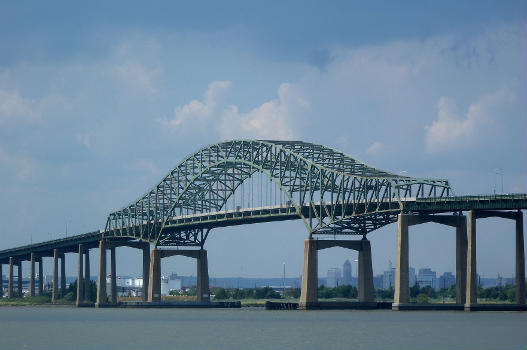 Looking northwest, full zoom, from hill in wetlands park in northwestern Bayonne, at bridge on a partly cloudy midday.