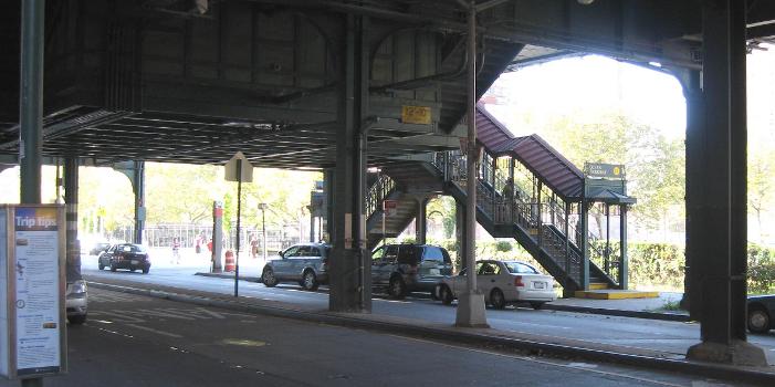 Looking north across Brighton Avenue, underneath the Brighton Line at en:Ocean Parkway (BMT Brighton Line) station stair on a sunny afternoon