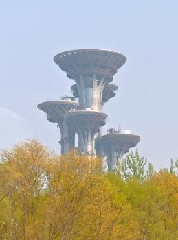 Olympic Park Observation Tower, designed by Cui Kai, Li Cundong and Zhao Wenbin, over trees in Olympic Green, Beijing.