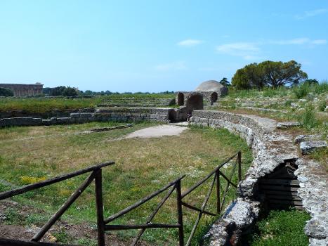 Amphitheatre, looking to west entrance, Paestum:Temple of Neptune is beyond to the left