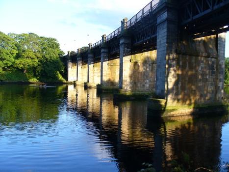 Railway Bridge Over the Dee : The downstream side of the railway bridge catches the evening light. The river is tidal here and is used for recreation - anglers and rowers.