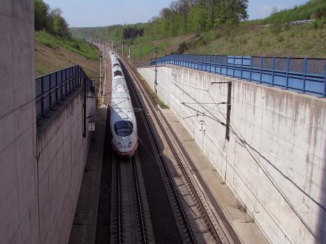 Ein ICE 3, auf dem Weg von Köln nach Frankfurt, fährt bei Wiesbaden-Auringen in das Nordportal des Schulwaldtunnels ein:Mit einer Länge von 4.500 m ist er der längste der 30 Tunnel der Schnellfahrstrecke Köln–Rhein/Main.