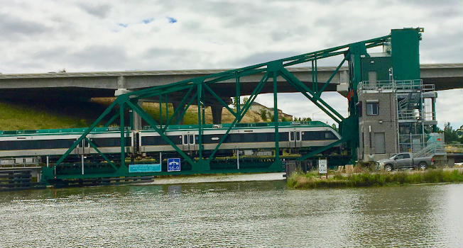 A northbound SMART train crosses the Petaluma River on a drawbridge previously used on the Galveston Causeway.